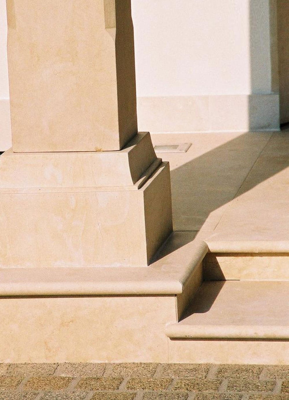 Sandsteinsockel einer Säule mit profilierter Bank und Stufen im warmen Streiflicht