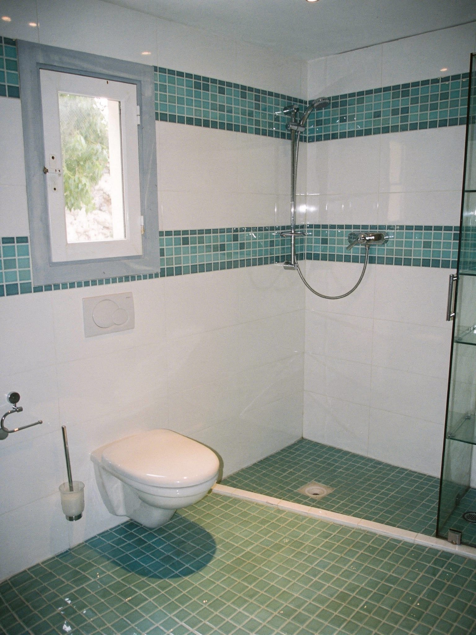 Bad mit grünem Glasmosaikboden, weißen Wandfliesen und türkiser Mosaikbordüre, offene Dusche