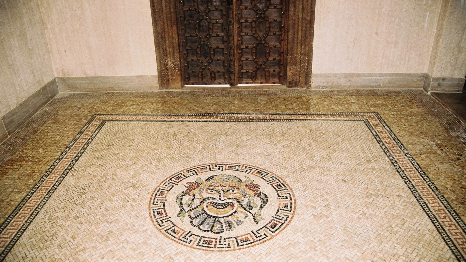 Fischgrat verlegter Natursteinmosaik-Boden mit Mäander-Bordüre und rundem figürlichem Mosaikmedaillon in einem Entree