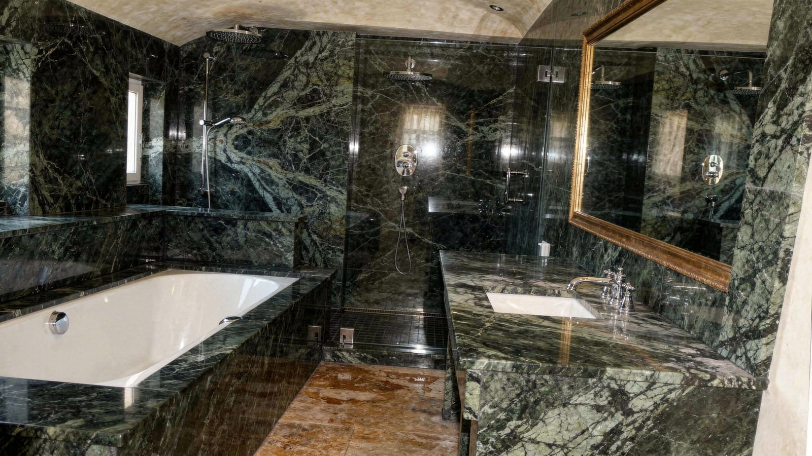 Badezimmer mit dunkelgrünem, geädertem Marmor an Wänden, Waschtisch und Wanneneinfassung, warmes Tageslicht